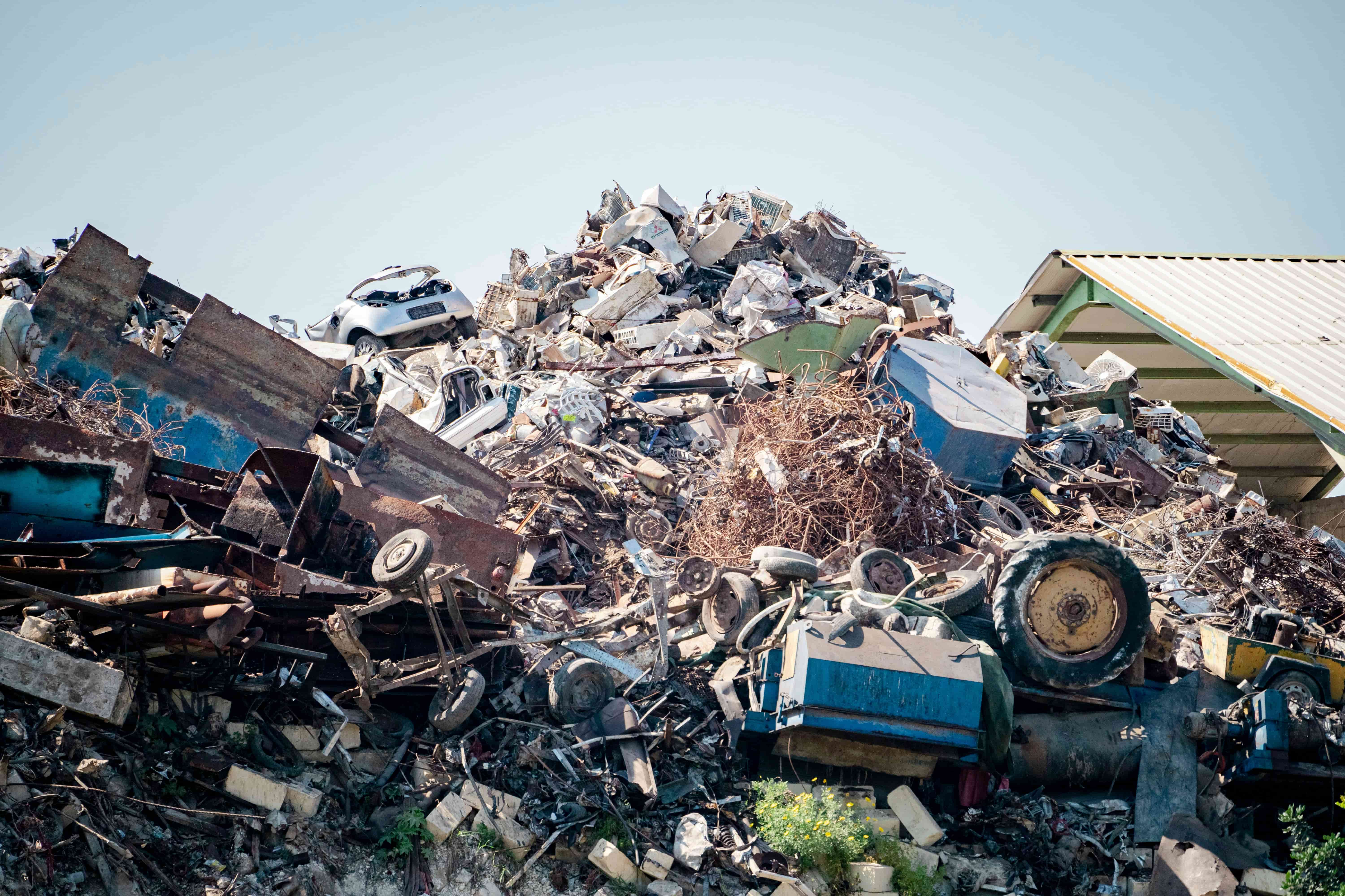 Montón de chatarra metálica variada en un centro de reciclaje en Navarra, con señales de gestión de residuos visibles al fondo